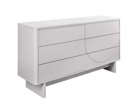 Modern&aacute; art deco &scaron;irok&aacute; komoda Savonia so &scaron;iestimi z&aacute;suvkami s geometrick&yacute;m reli&eacute;fom v tvare vlny z dvoch polobl&uacute;kov na dvoch ploch&yacute;ch noh&aacute;ch s keramickou mramorovou doskou v bielej farbe