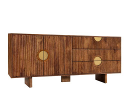 Dizajnov&yacute; art deco obdĺžnikov&yacute; pr&iacute;born&iacute;k Tores z mas&iacute;vneho mangov&eacute;ho dreva v pr&iacute;rodnej hnedej farbe s dvojdverovou skrinkou a dvomi z&aacute;suvkami s asymetricky umiestnen&yacute;mi okr&uacute;hlymi &uacute;chytkami a rebrovan&yacute;m reli&eacute;fom v zlatej farbe s tromi ploch&yacute;mi &scaron;irok&yacute;mi nohami