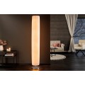 Moderná vysoká stojaca lampa s oválnym valcovitým tvarom, rebrovaným bielym tienidlom a kruhovou kovovou podstavou v chrómovom prevedení.