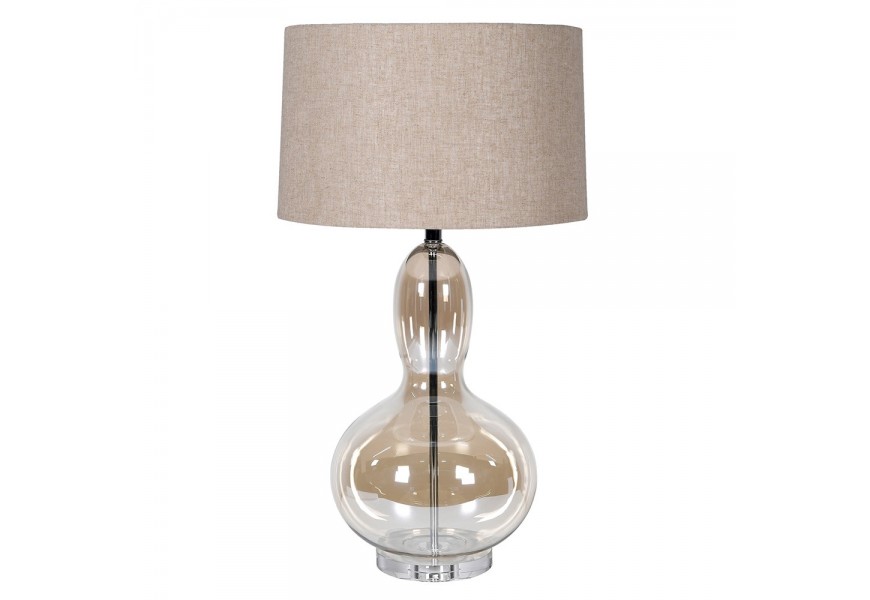 Dizajnová glamour stolná lampa Kayla s nohou z priehľadného skla s hnedým tónovaním so zaoblenou siluetou v tvare hrušky s okrúhlym béžovým ľanovým tienidlom a kovovou konštrukciou v lesklom chrómovom prevedení